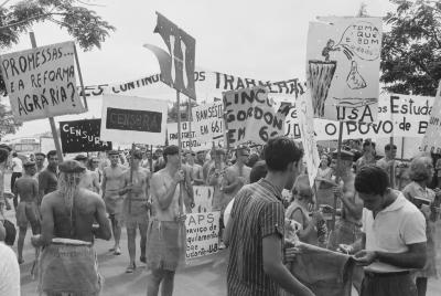 Calouros com roupa de estopa desfilam pela avenida W3 segurando cartazes como parte do trote da Universidade de Brasília