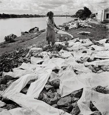 Mulher estendendo roupa na beira do rio