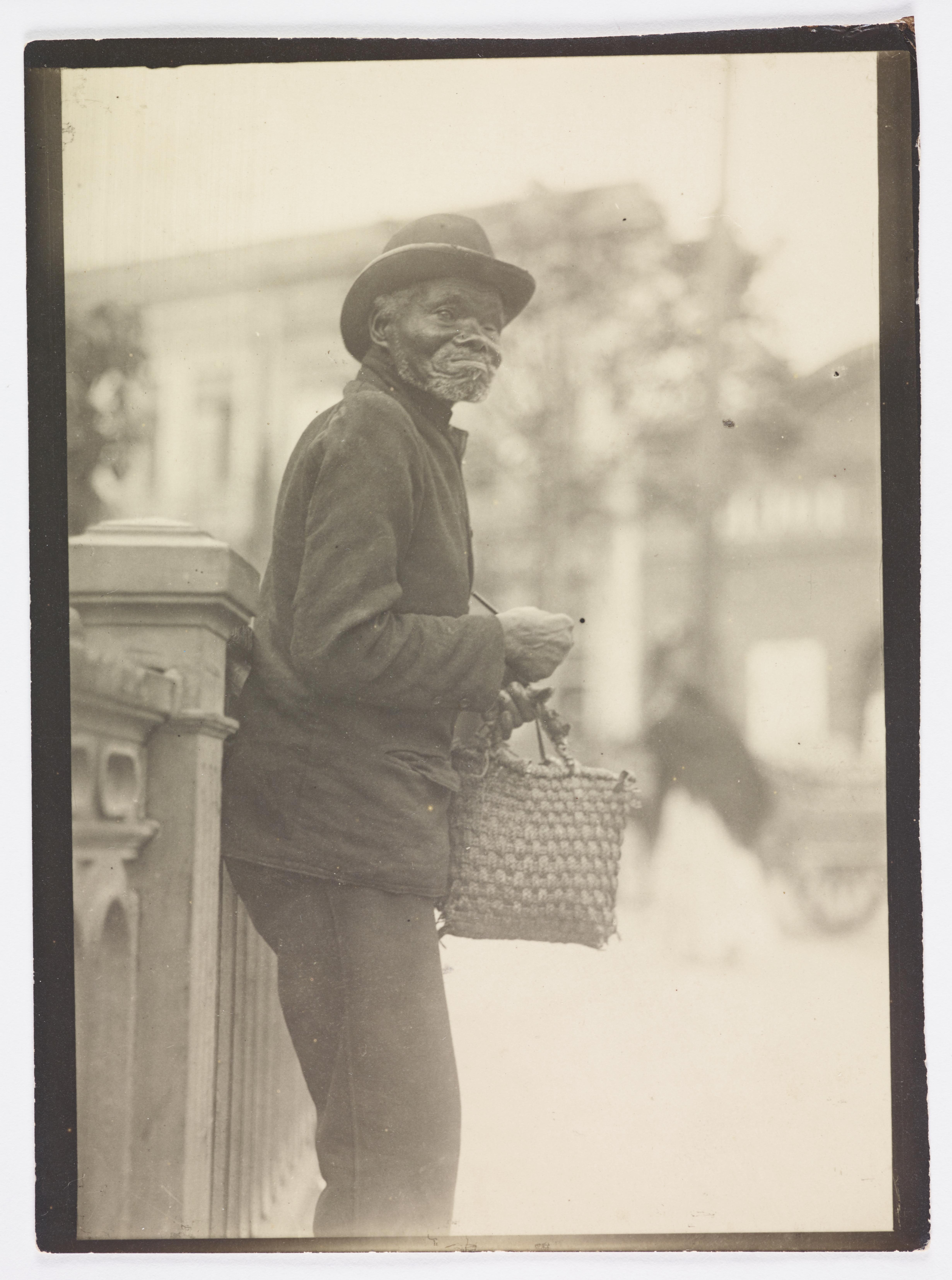 Retrato de homem idoso recostado em grade metálica