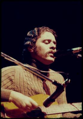 Chico Buarque ao microfone com o violão