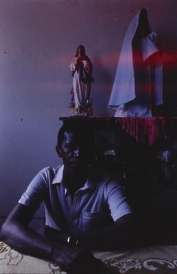 Homem não identificado, ao fundo escultura religiosa