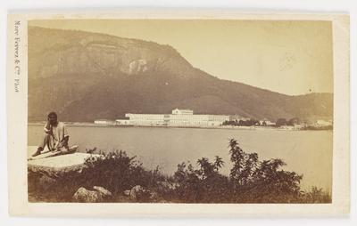 Homem posa para foto; ao fundo, o Hospital Nacional de Alienados (atual UFRJ)