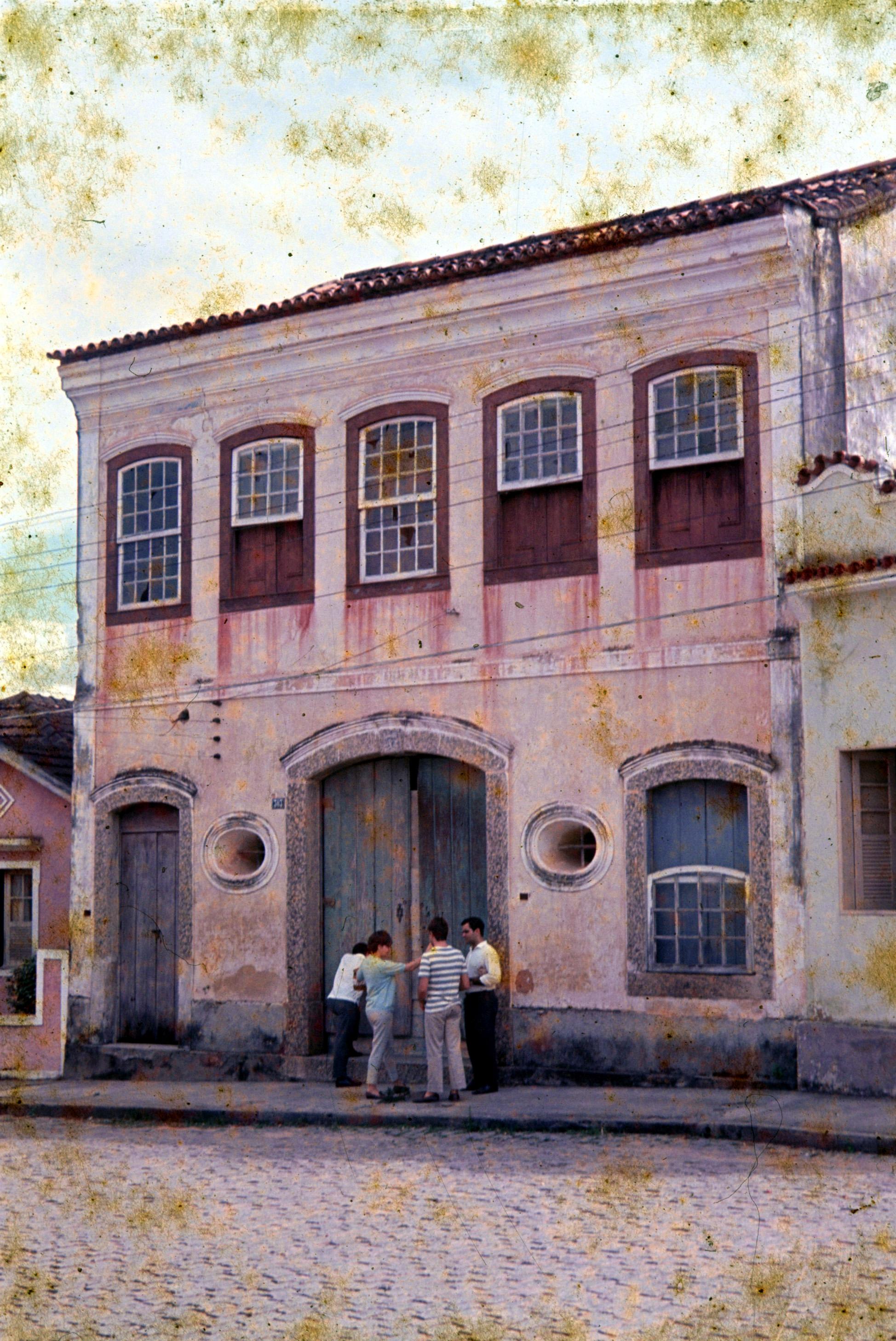 Pessoas reunidas em frente a um sobrado