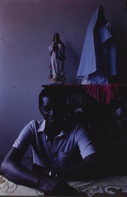 Homem não identificado, ao fundo escultura religiosa