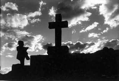 Menino camponês orando perante a cruz