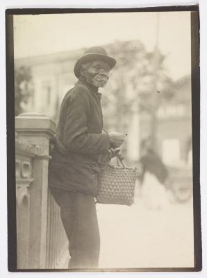 Retrato de homem idoso recostado em grade metálica