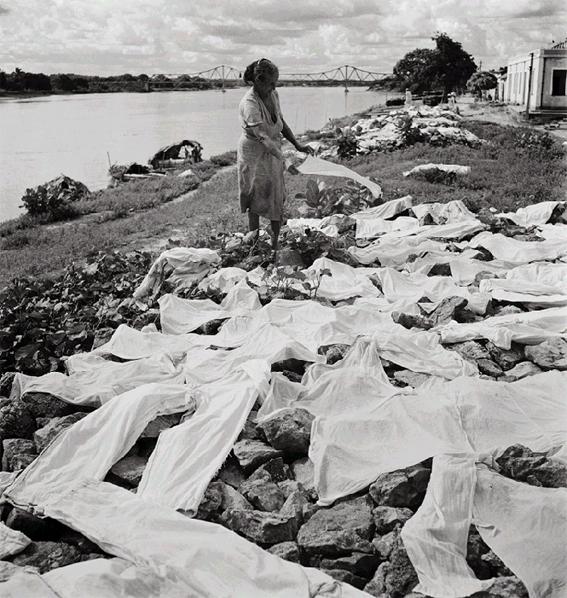Mulher estendendo roupa na beira do rio