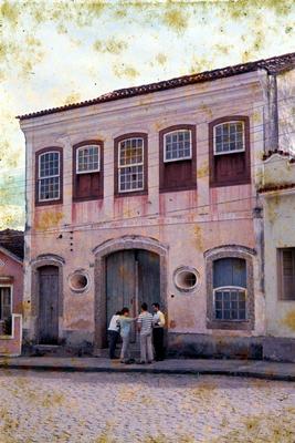 Pessoas reunidas em frente a um sobrado